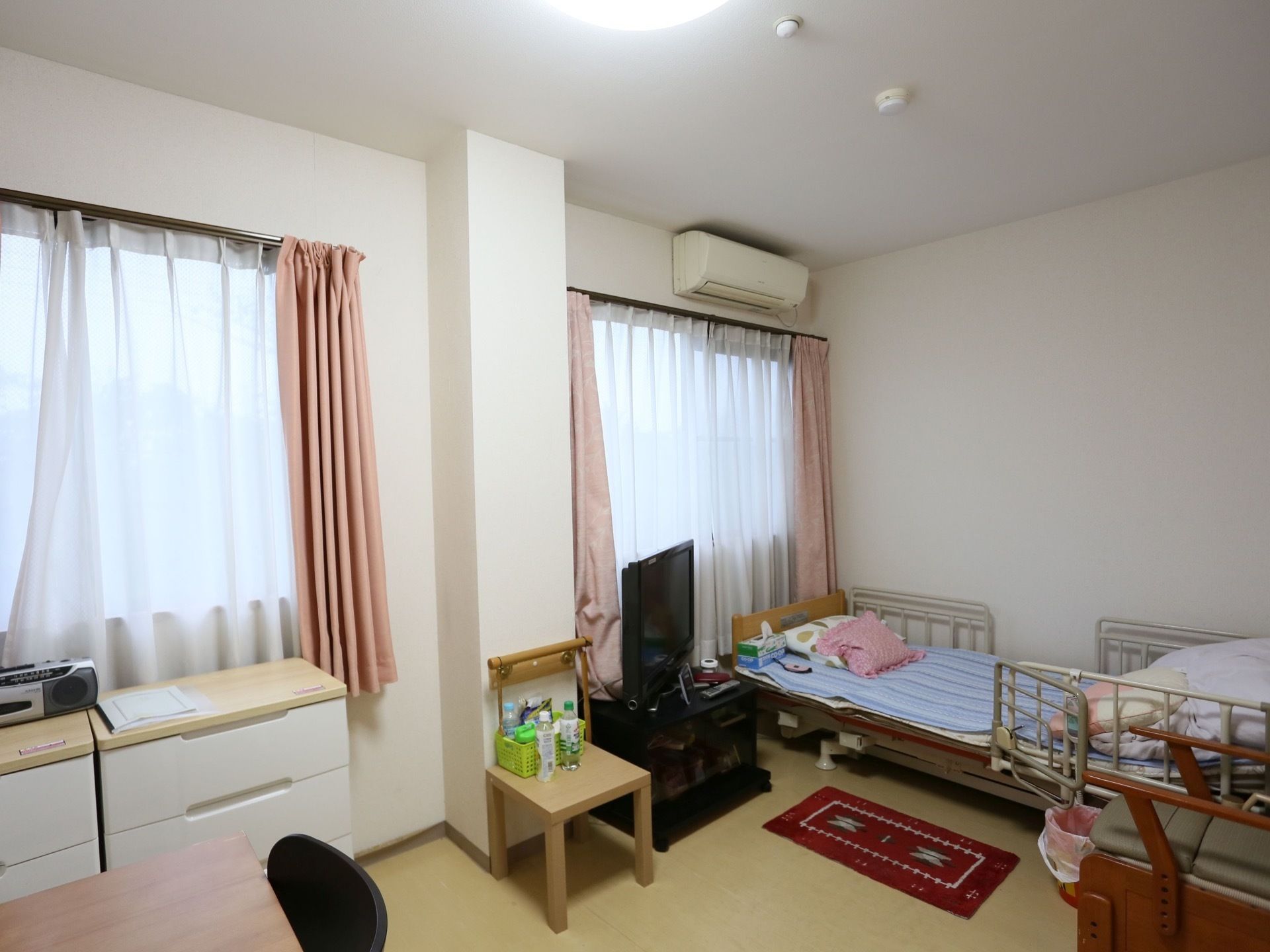 居室は広くて窓が多い。エアコンや介護ベッドのほか、入居者様の持ち込み家具や家電などが多数置かれている。