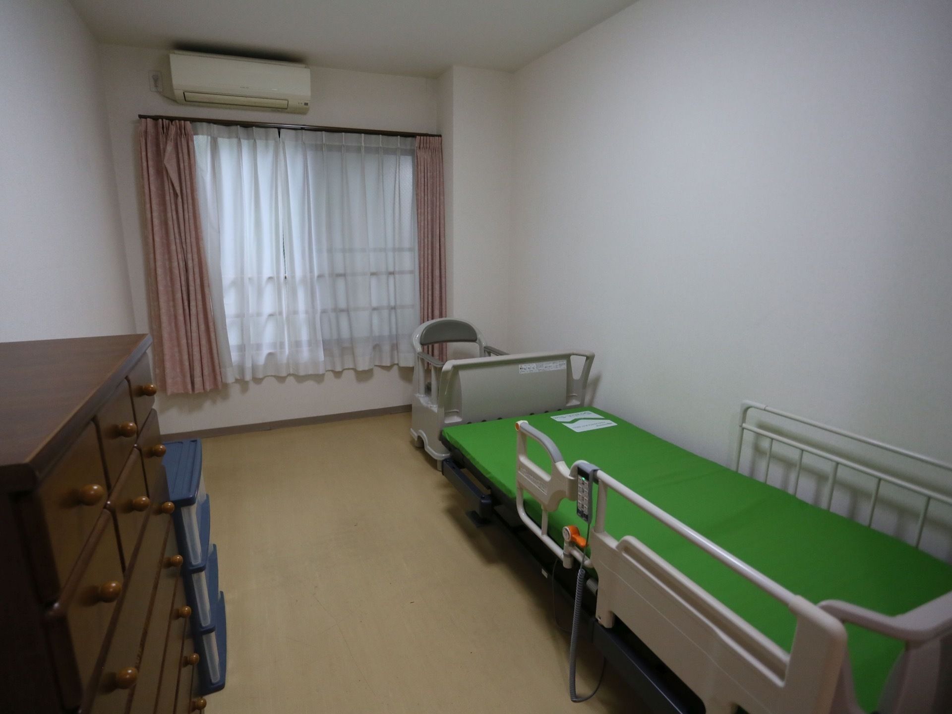 居室にはリクライニング可能な電動ベッド、引き出しのたくさん付いた収納棚、エアコンが備わっている。移動しやすいフラットフロアである。