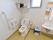 広々としたトイレに、洗面台と鏡を設置している。小窓があり、明るい光が差し込んでいる。手すりは２か所に設置している。