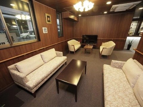 褐色の壁と床に、白い大きなソファが机を挟んで向かい合わせに置かれている。その隣にも白いソファセットがあり、突き当りにはテレビがある。