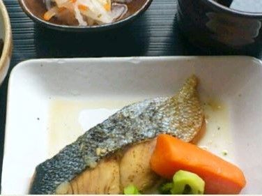 黒色のお盆に料理が並べられている。メインは白皿に盛り付けられたお魚。ほかにも小鉢などがあり、酒類豊富な料理を味わえる。