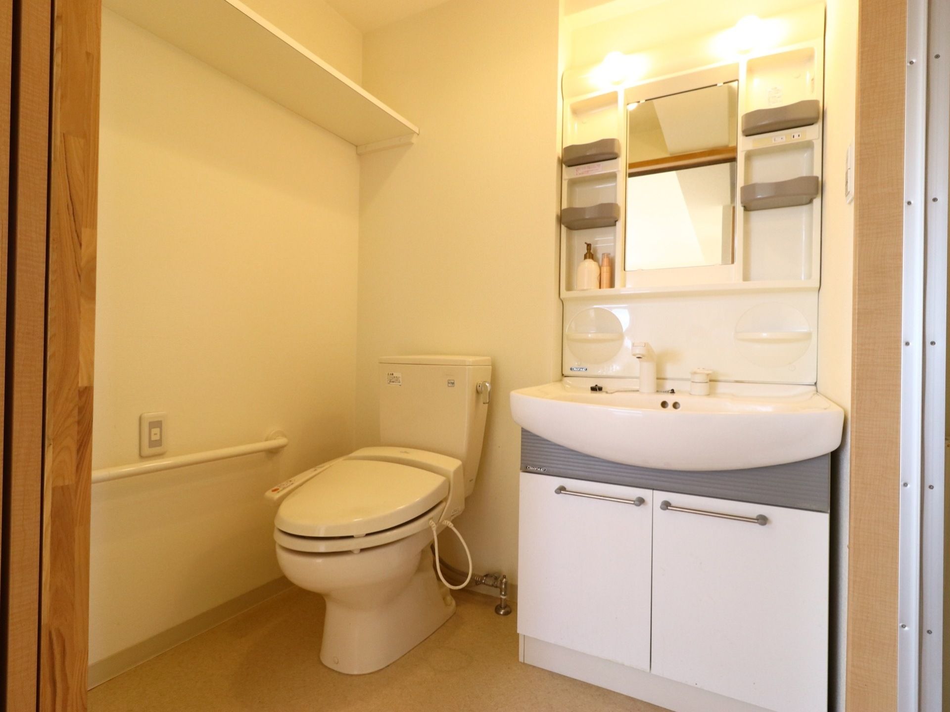 トイレの壁にはL字型の手すりや緊急呼び出しボタンが設置されている。上部の棚はトイレットペーパーなどを置くことができる。