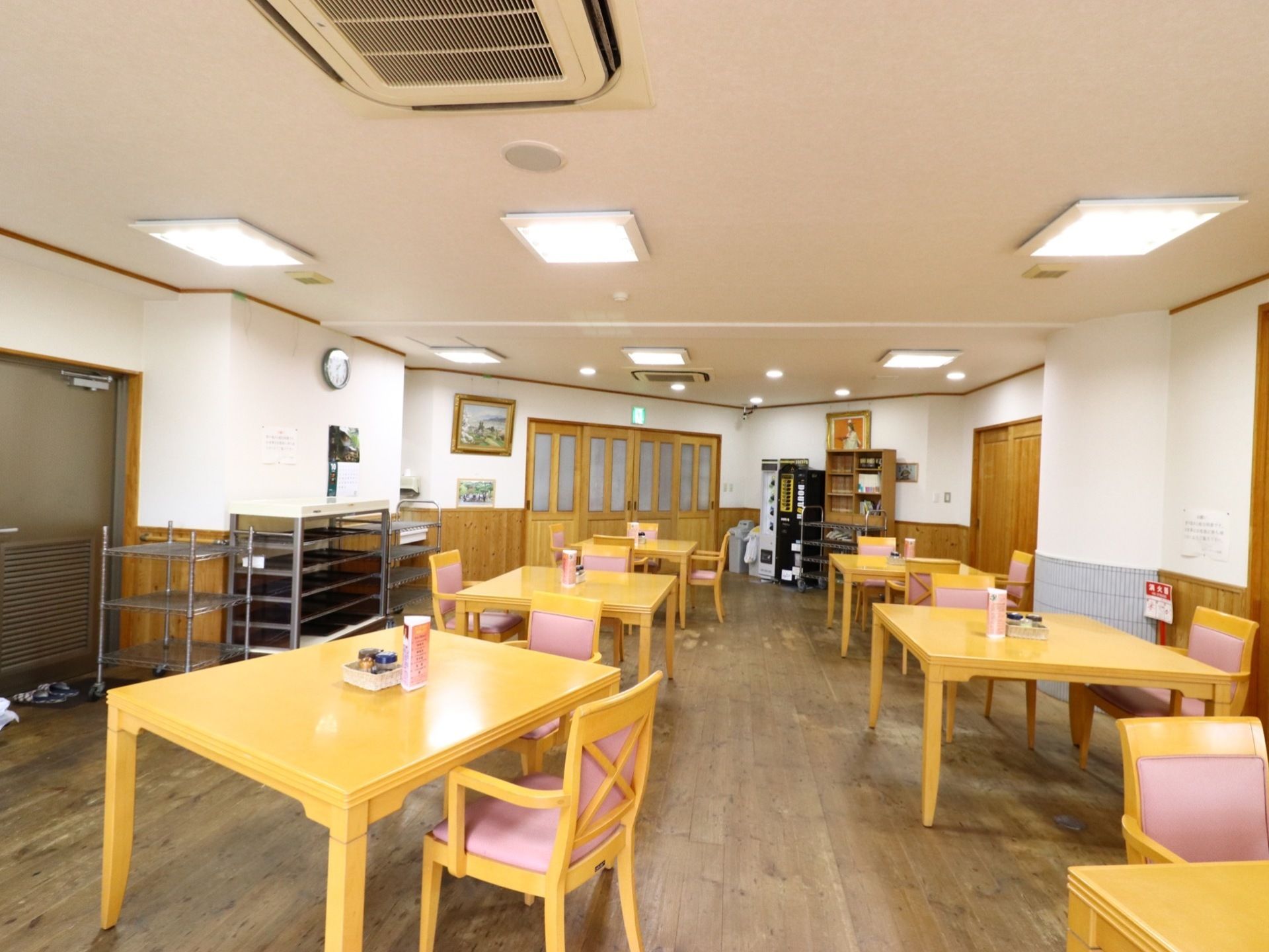 明るい色のテーブルと椅子がたくさんある。左の壁際には、食べ終わったお盆を下げるための棚が置かれている。