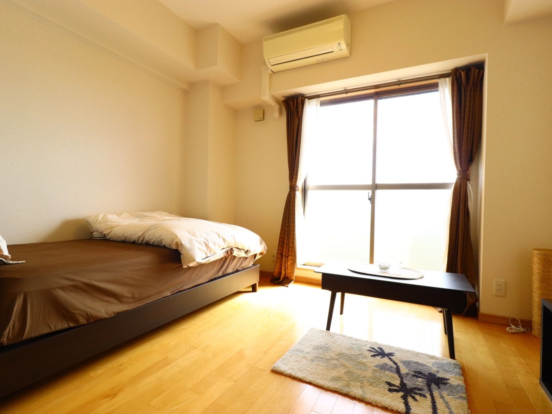 大きな窓のある明るい居室はベッドがあっても広く使える。エアコンが設置されているので、入居者様の好みに合わせた温度設定が可能。
