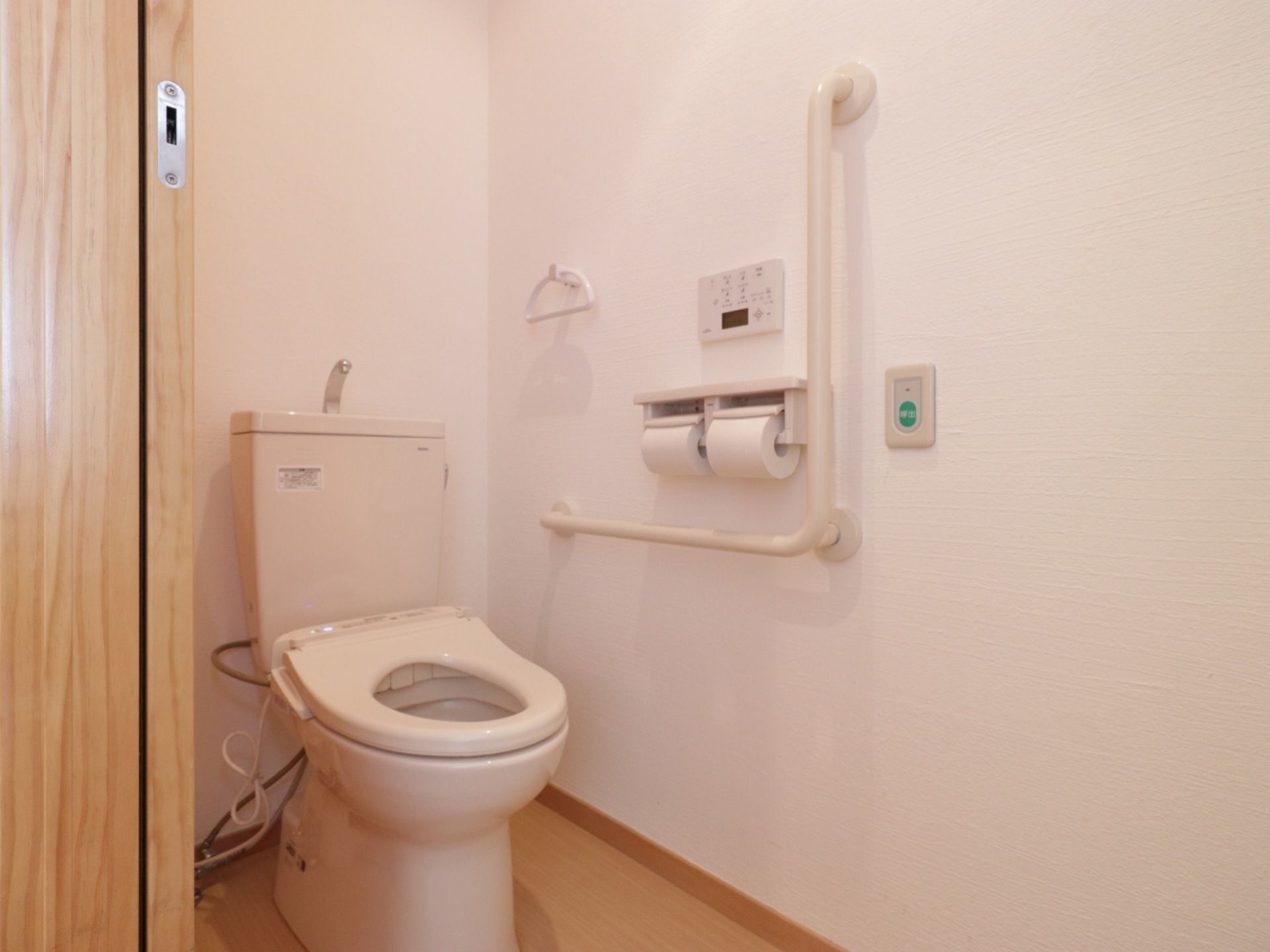 トイレは洋式トイレが設置され、白い壁とベージュの床になっている。壁にはタオルハンガーが取り付けられている。