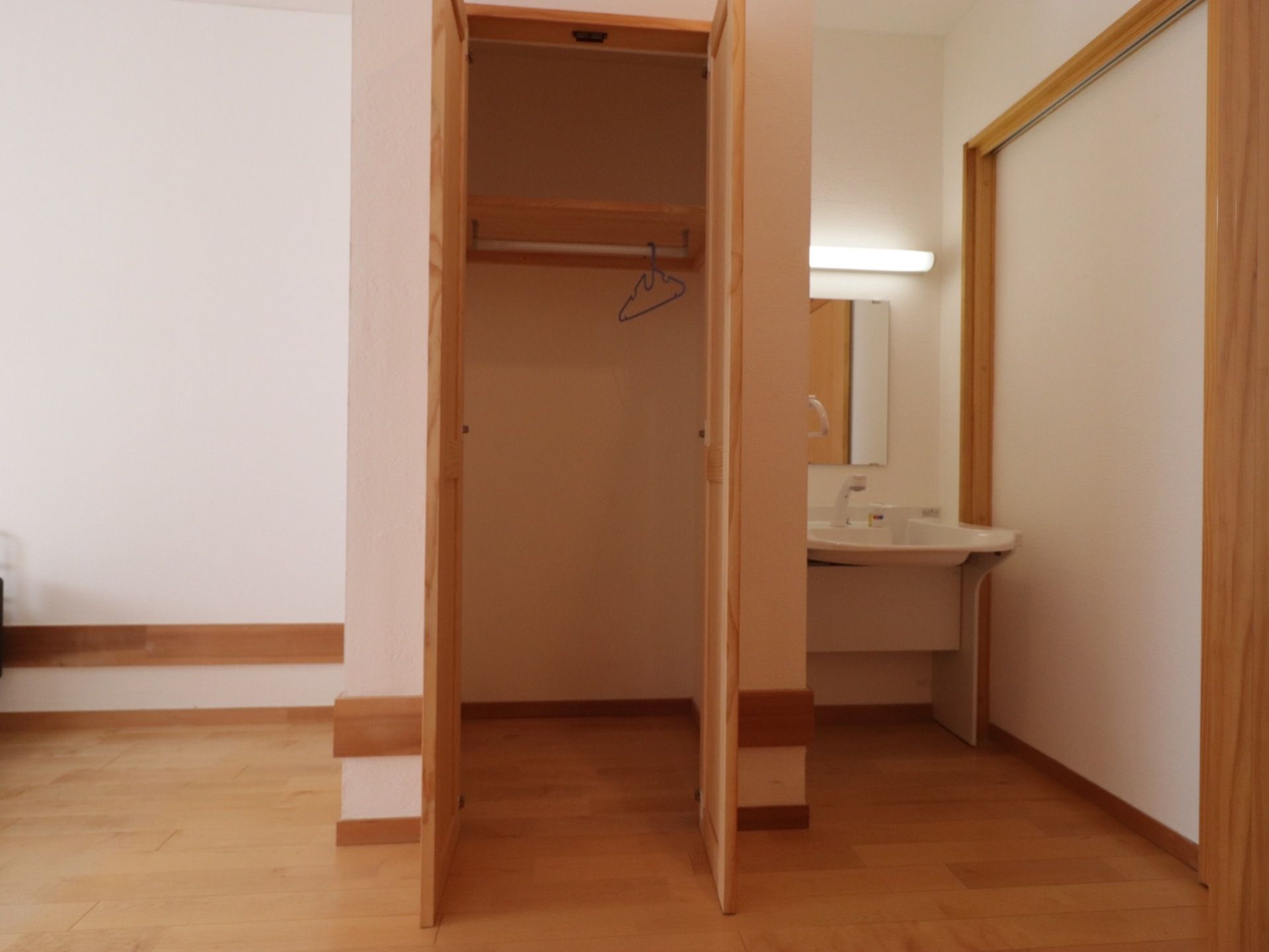 両開きの扉の付いたクローゼットを設置している。上部に棚があり、ハンガーが掛けられるポールが設置されている。