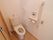 洋式トイレが設置されている。壁に手すりや呼び出しボタン、温水洗浄便座用のボタンが取り付けられている。