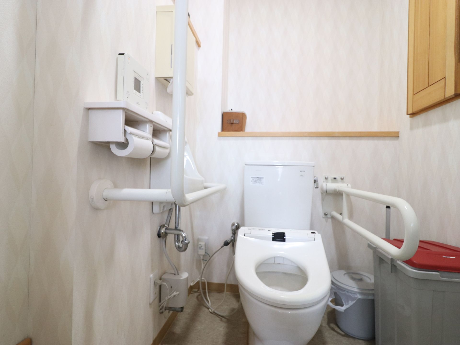 トイレの両側に、手すりが取り付けられている。右側はL字、左側は可動式の手すりである。個室の一角にゴミ箱が置かれている。