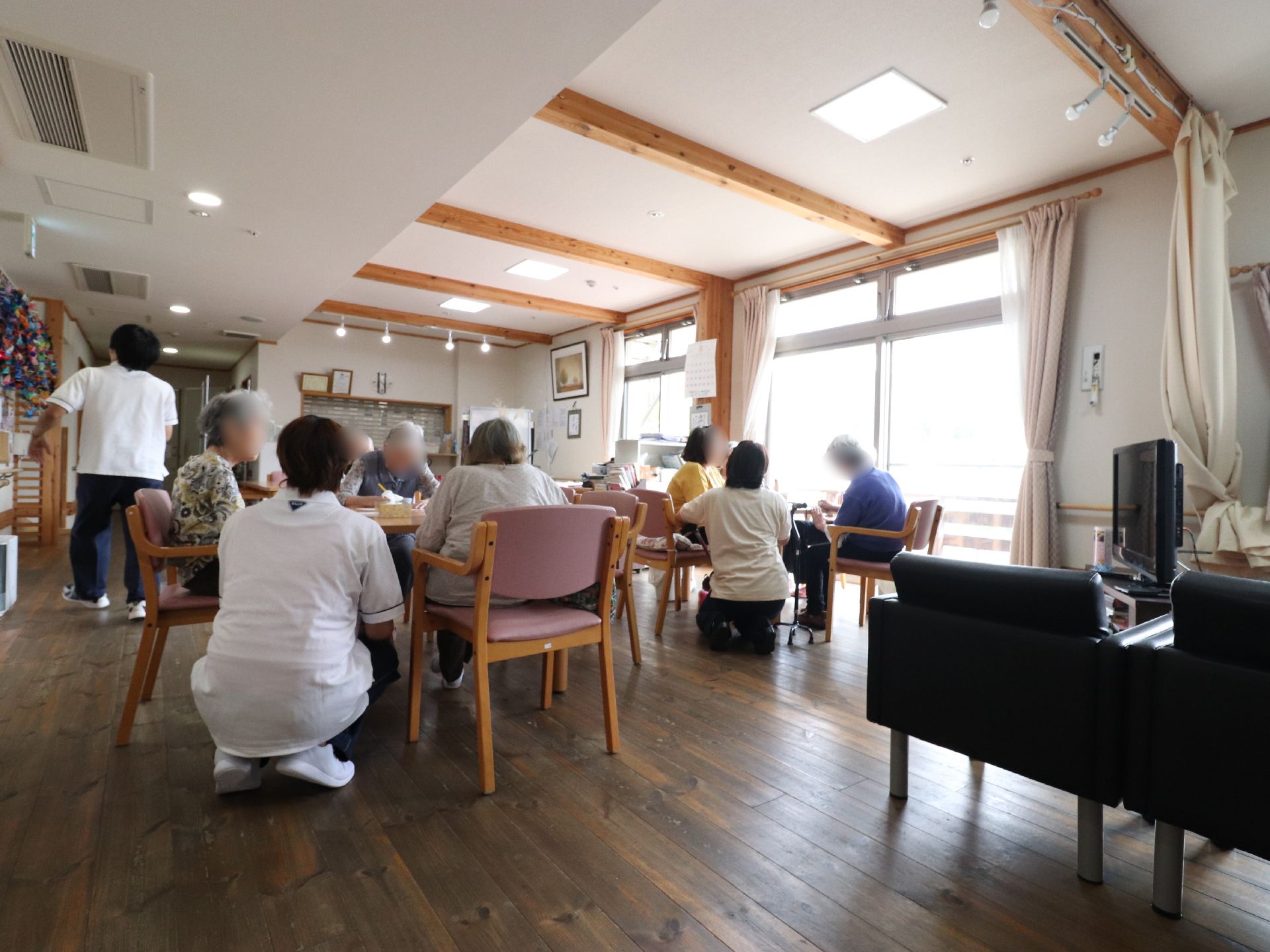 共用スペースでテーブルを囲んで会話や作業をしているスタッフとご入居者様