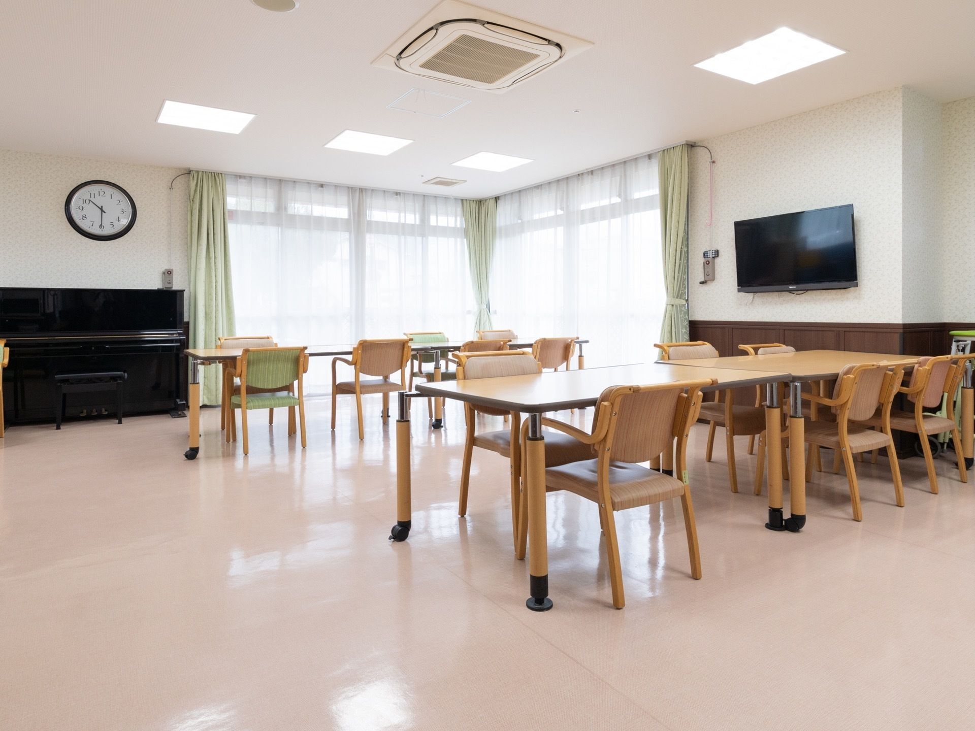 壁にスタンドピアノやテレビが置かれた二面採光の共用スペース