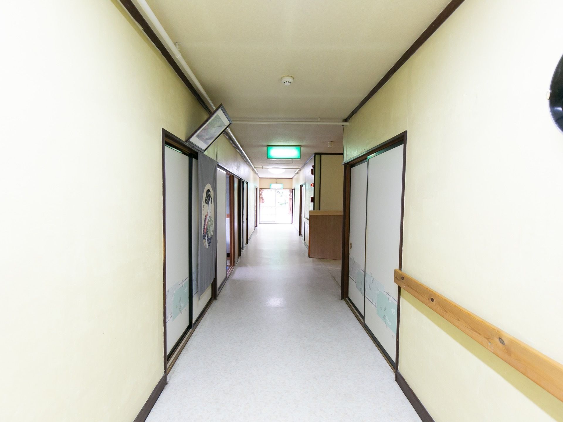突き当りの窓から光が入る明るい廊下である。手すりが設置されており、移動の際に体を支えることができる。