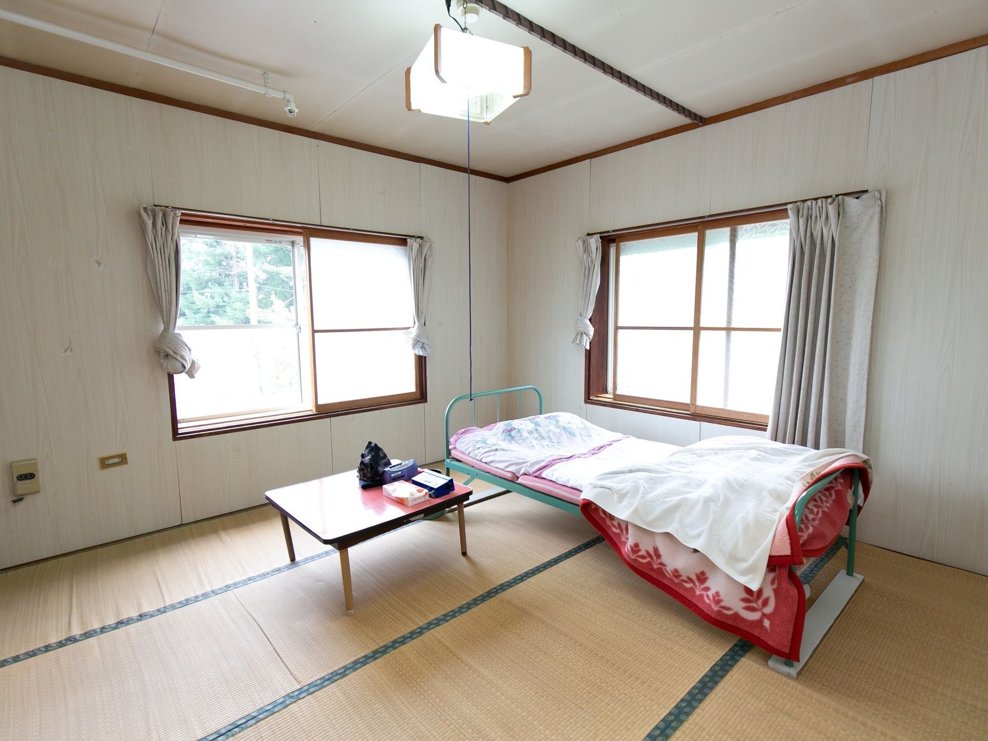 畳敷きの個室で、テーブルとベッドが置かれている。腰高窓が2か所取り付けられ、明るい陽射しが室内に射し込んでいる。