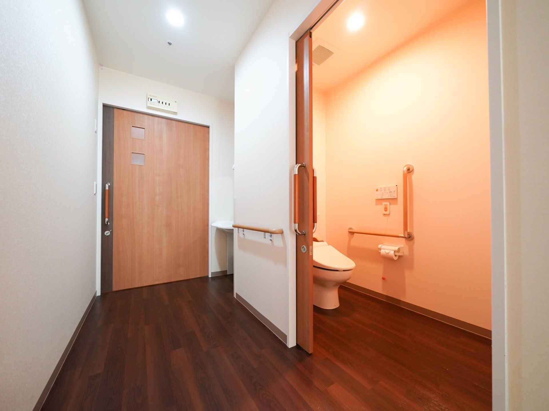 居室のドアを開けるとすぐに洗面台が設置されている。その隣にはトイレのドアがある。ドアはスライド式で開け閉めしやすい。