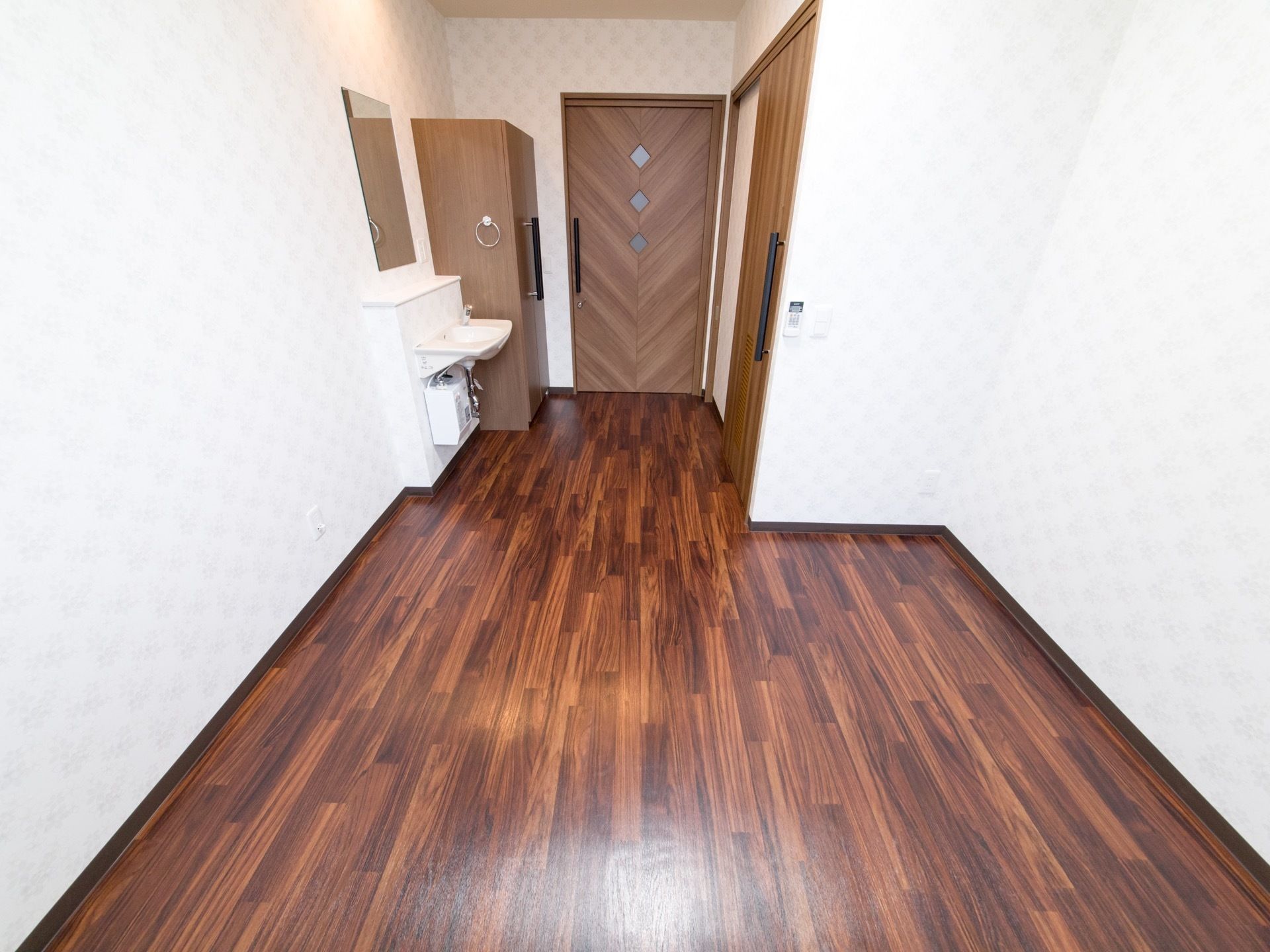居室の様子。ベッドやタンスは置かれておらず、シンプルな部屋である。入り口付近には、洗面台やクローゼット、トイレなどがある。