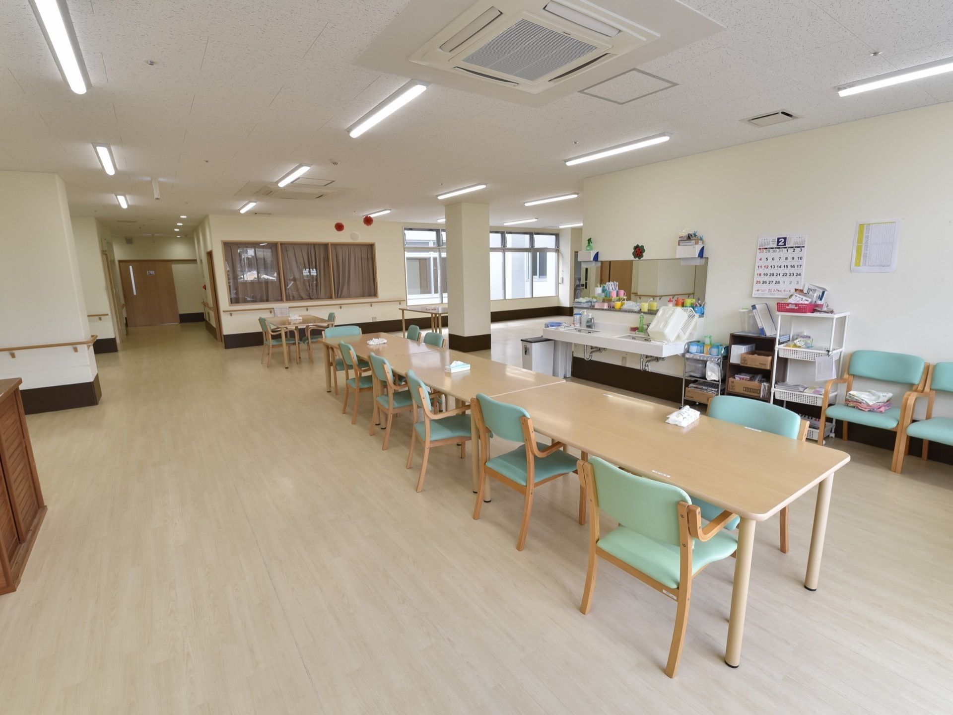 中央にダイニングテーブルが横一列に並べられている共用スペース