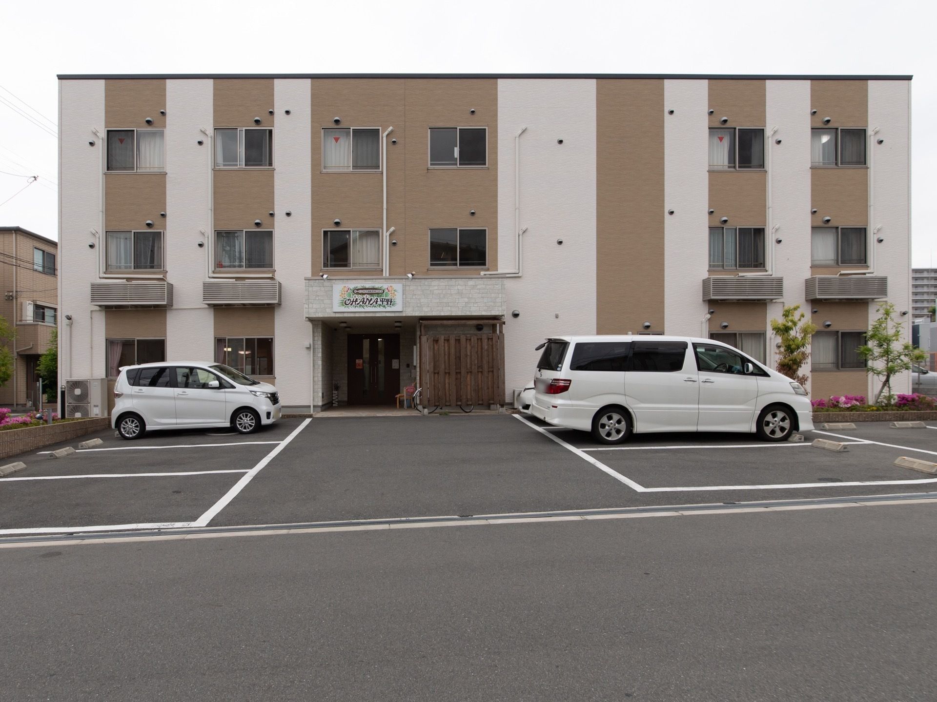 施設前は駐車スペースを多く用意しており、車でのご来館が可能となっている。建物周囲には樹木や低木などの植栽が植えられている。