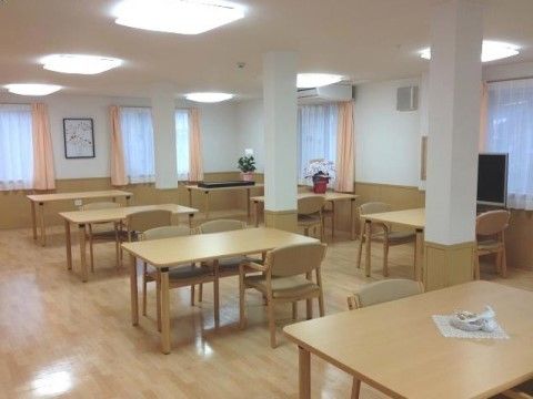 4人掛けテーブルが並んだ白とベージュを基調とした明るい食堂