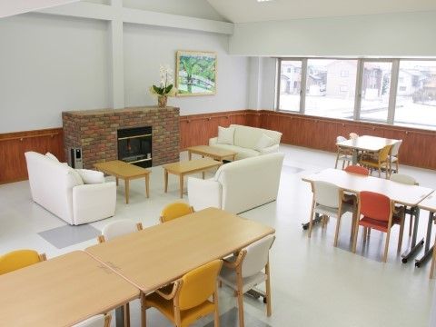 壁に手すりが設置され、暖炉風の暖房器具が置かれ、ソファやテーブルが並んだ食堂