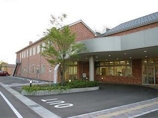 赤いタイル張りの２階建ての建物。玄関前には大きな木の植栽がある。敷地内は舗装されており、入口から玄関まで点字ブロック付きの歩道がある。