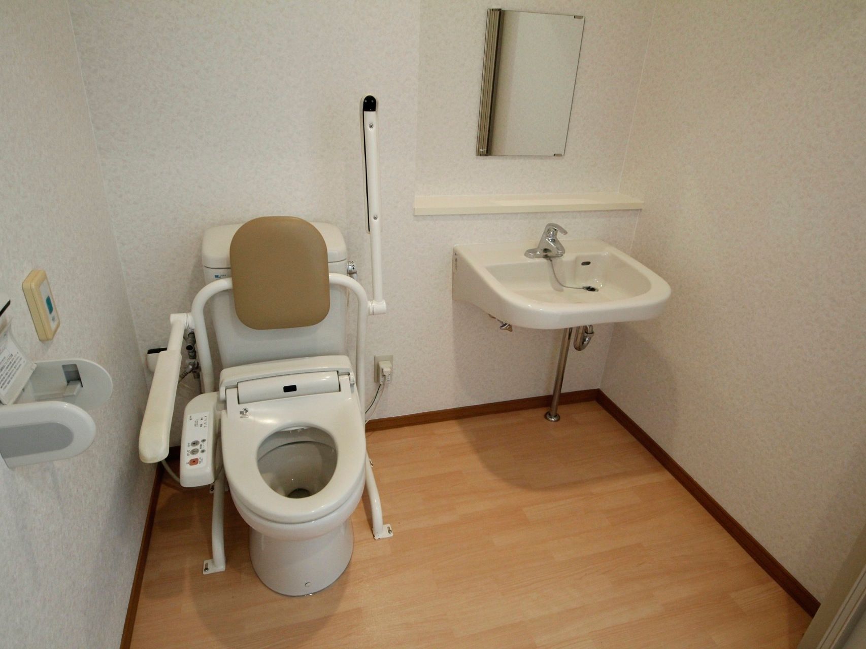 とても広い個室である。洗面台と鏡も個室内に設置されている。便器の両脇に手すりがある他、背面にクッションが付いている。