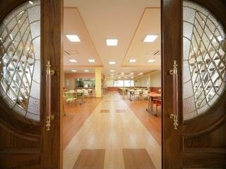 レトロなデザインの木製ドアから覗く広々としたテーブルがたくさん並ぶ共有スペース