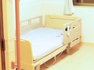 扉近くに手すりが設置され、転落防止柵が付いた介護ベッドが置かれた居室
