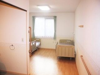 ベッドが２台置ける広々としたフローリングのお部屋である。お部屋の中にも手すりがあるので、スムーズに移動ができる。