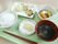 緑色のトレイに食事が盛り付けてある。ごはん、わかめと上げの味噌汁。赤いおはしが一膳ついている。おかずはほどよいサイズにカットしてある。