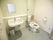 トイレの入口は引き戸になっている。洋式トイレと洗面台が並んで設置され、洗面台の鏡の前は棚になっている。