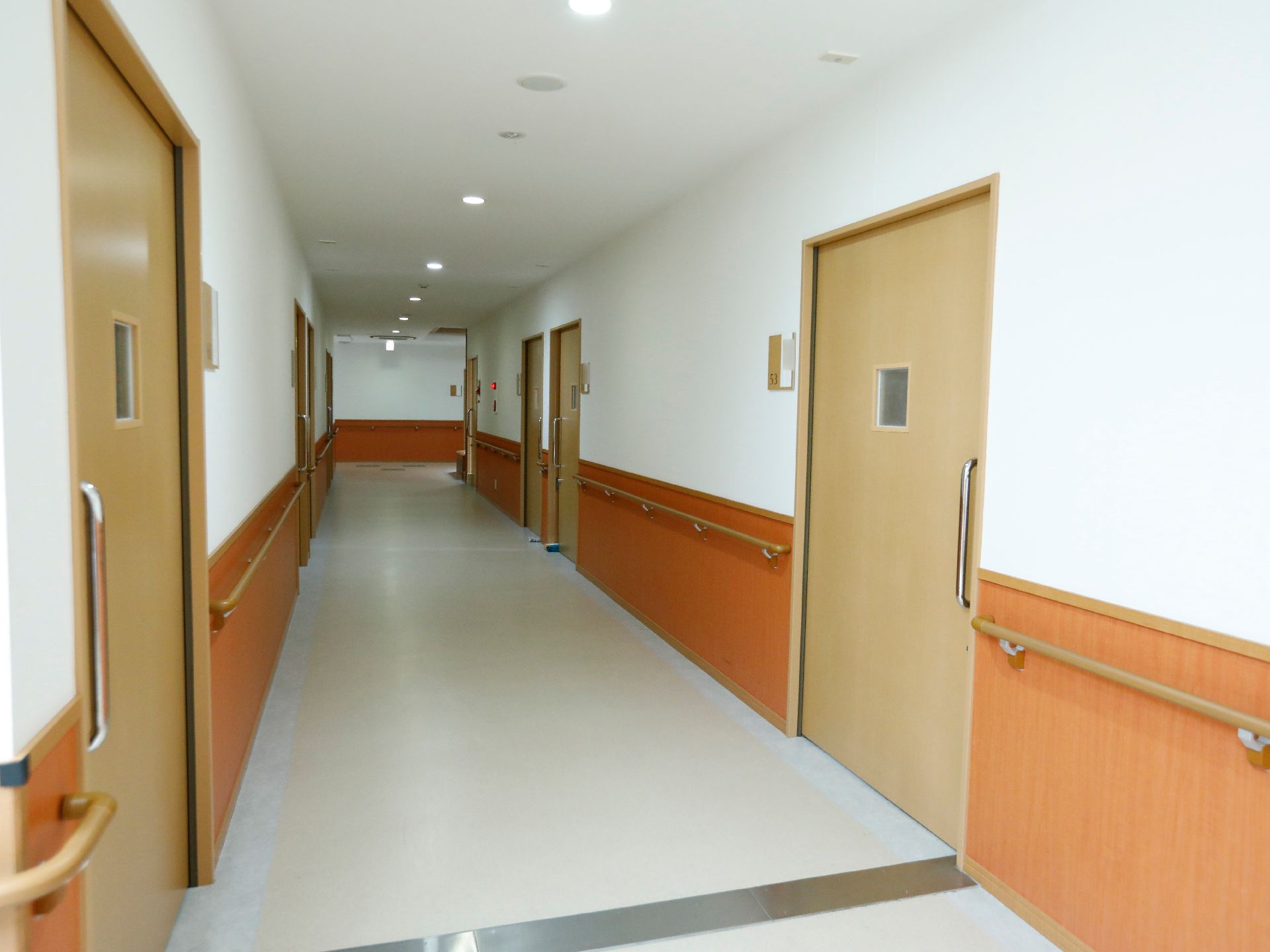 廊下の左右に手すりがあるので、足腰が弱ってきた高齢者でもしっかりと掴まりながら歩くことができる。壁に非常警報機が取り付けてある。