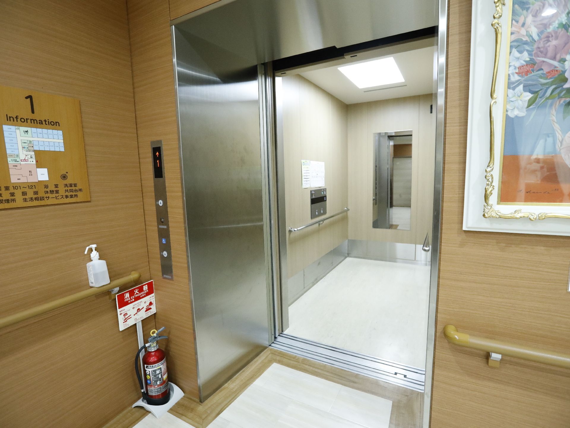 扉が開いたまま停まっているエレベーターがある。乗り降り口に段差がなくフラットである。手すりがあるので運転中はしっかりと掴まることができる。