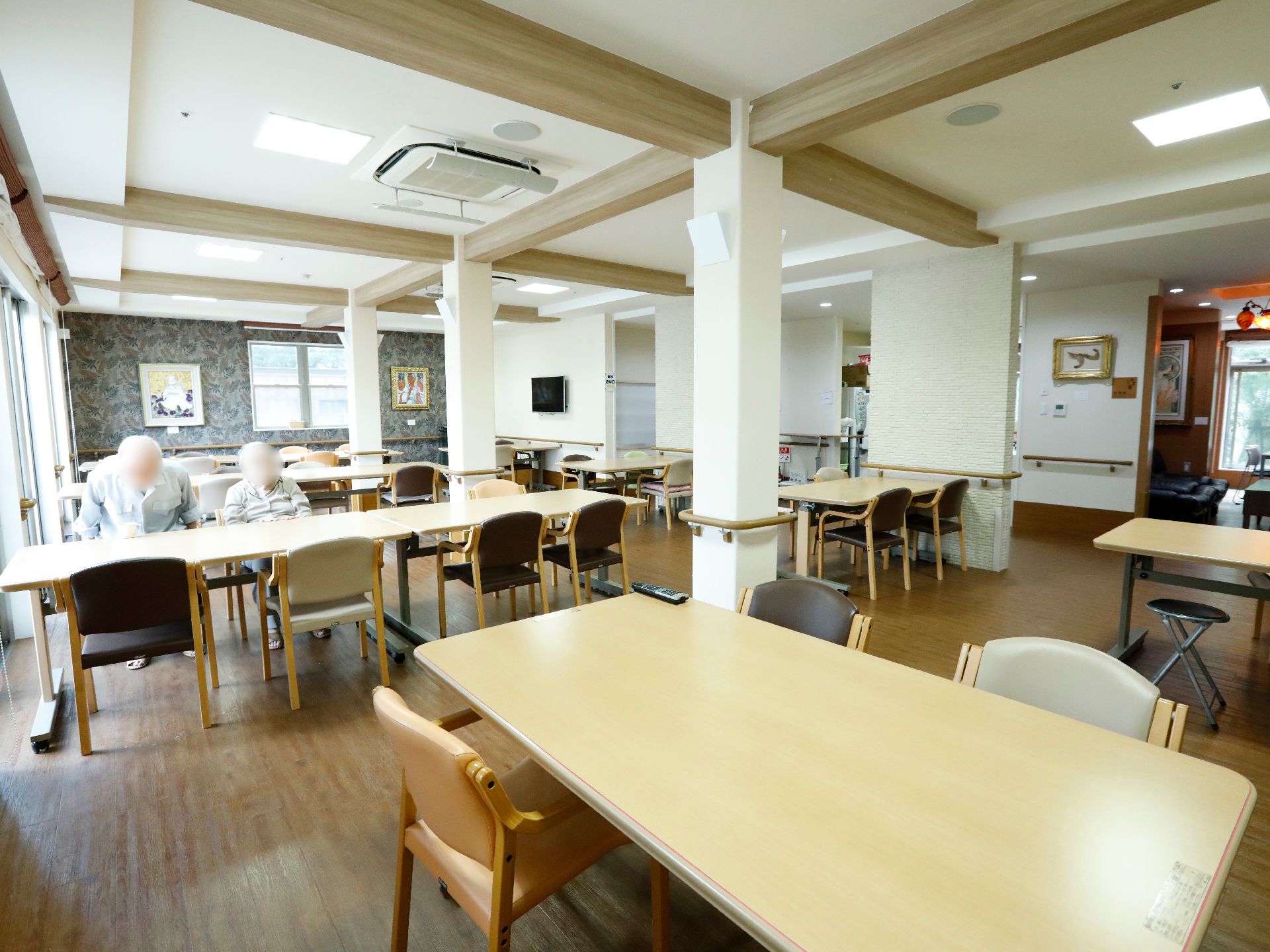 白い壁や柱に手すりが設置され、たくさんのテーブルが並ぶ食堂