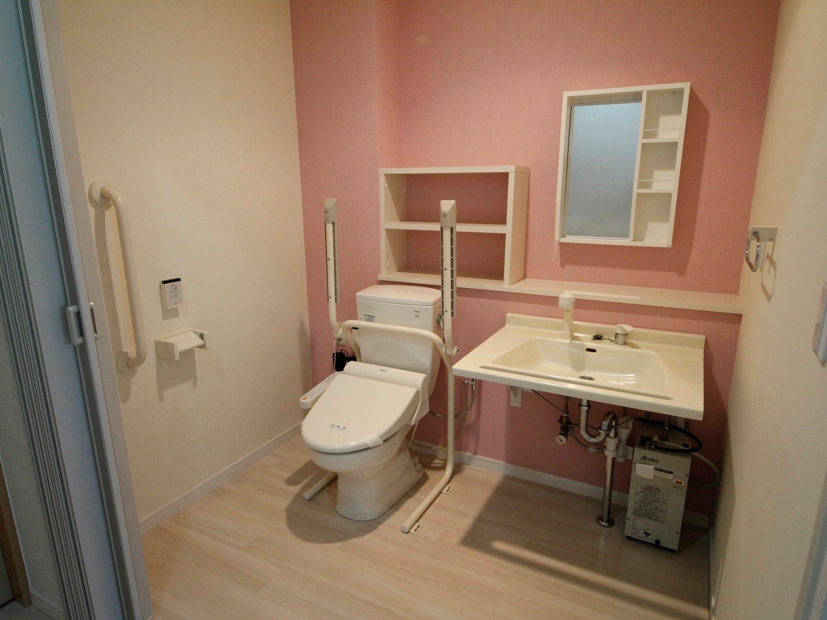 落ち着いたピンク系の壁がおしゃれな雰囲気の広々としたトイレには、たっぷりとした洗い場がある洗面台が設置されている。