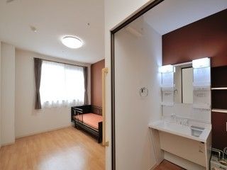 ダークブラウンの壁際に洗面台を設置している。鏡の両側にボックス棚があり、ソープや歯ブラシなどを置くことができる。