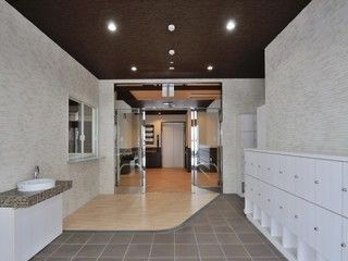 広々としたエントランスの横側に白い靴箱を設置している。反対側には洗面台を備え、傍にはソープや消毒液などが置けるスペースがある。