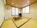 白色の壁と白木の天井に正面と横側に障子備えの窓がある。天井下にエアコンが設置され、テレビが置かれている。