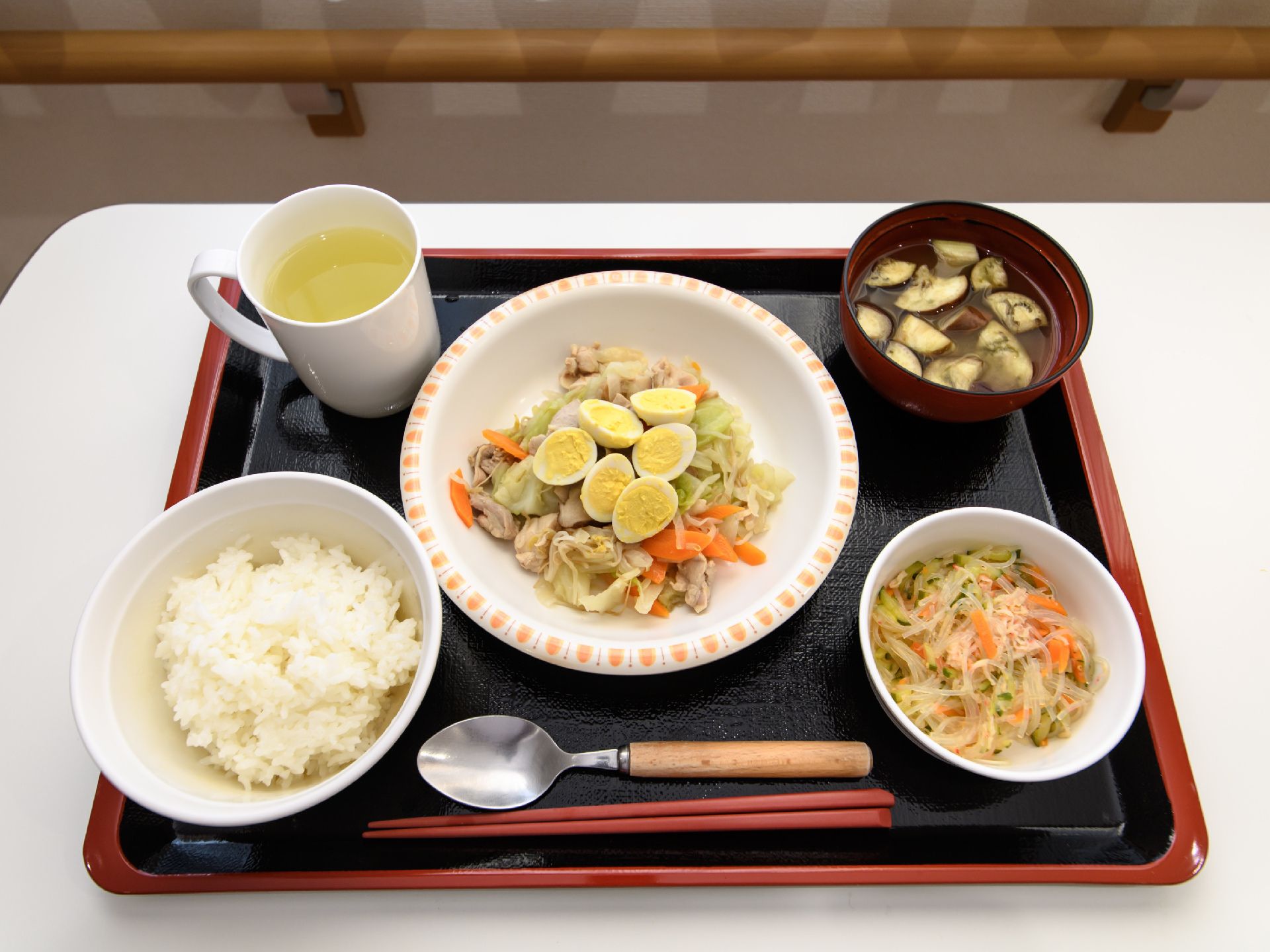 この日の献立のメインはうずらの卵が入った野菜炒め。ご飯に味噌汁、小鉢、飲み物が付いている。野菜をふんだんに使ったバランスの良い食事。
