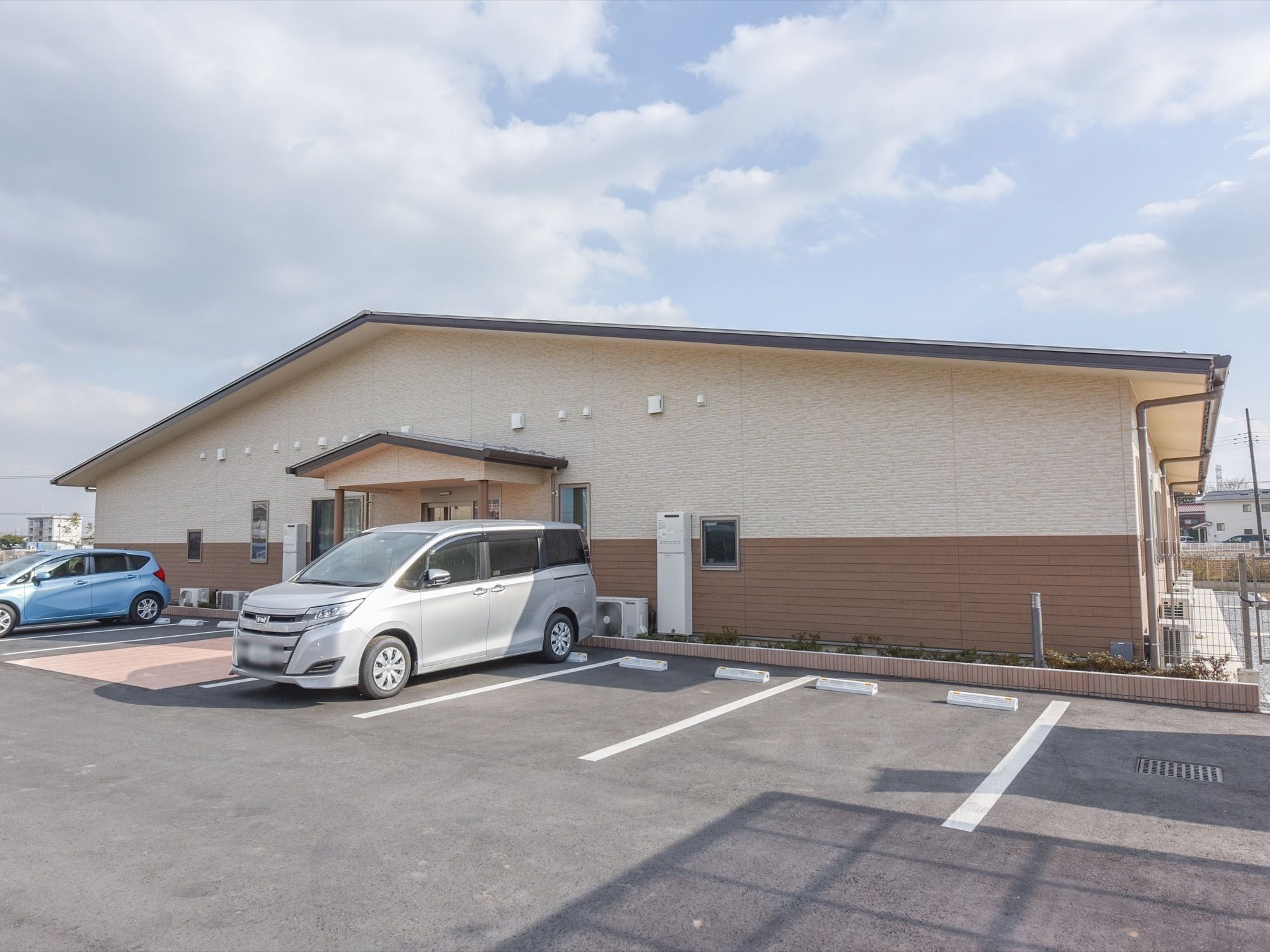 施設は１階建てで建てられている。外壁はベージュとブラウンを基調とした落ち着いた雰囲気になっている。広々とした敷地内に駐車場が設けられている。