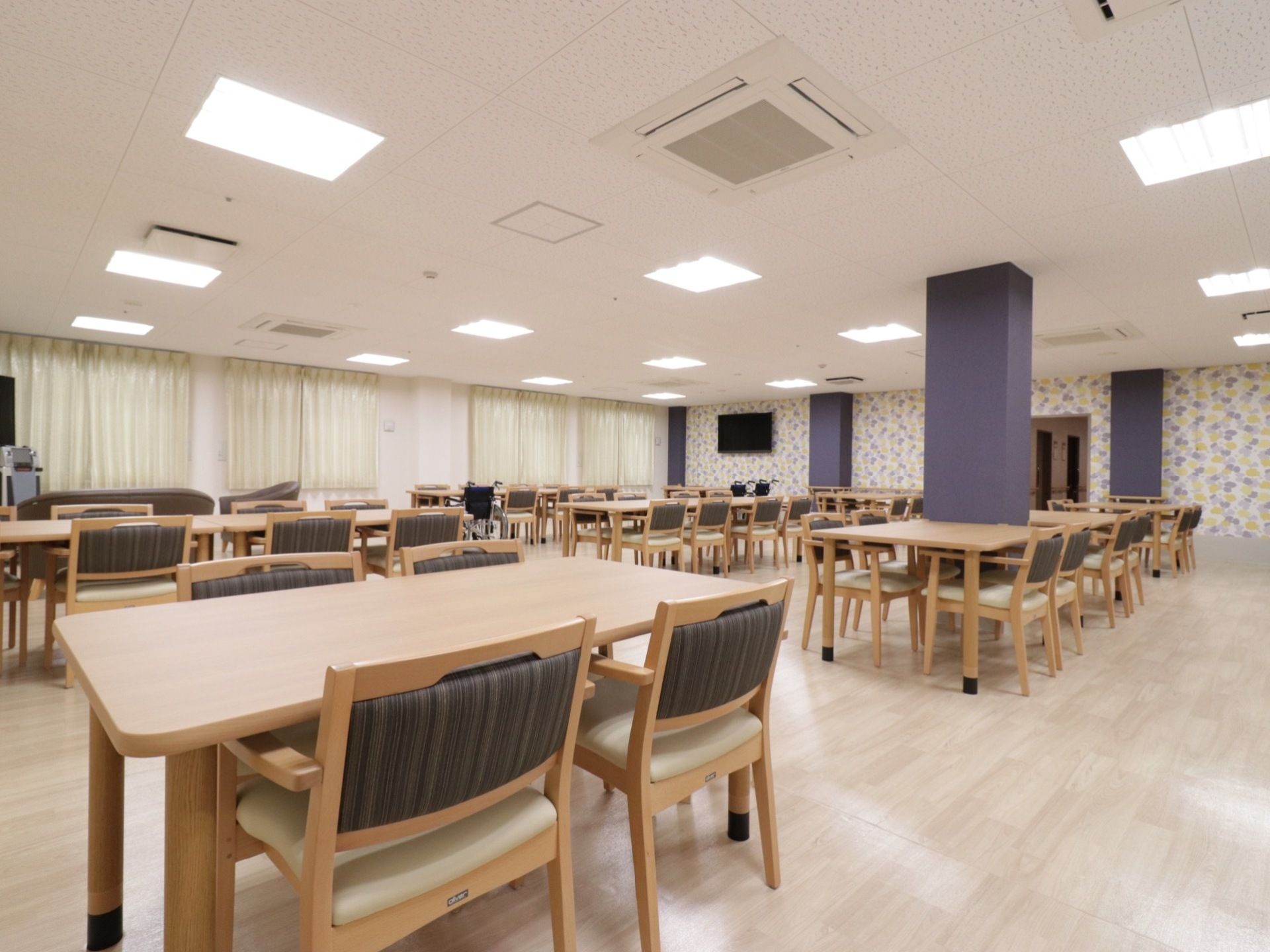 広々とした空間に椅子が備えられたテーブルが複数並ぶ食堂である。椅子は背もたれとひじ掛けが付いたものである。