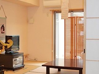 和室の畳の上に台が置かれ、テレビが載せられている。壁には掛け軸が掛けられ、部屋の中央にはテーブルが置かれている。
