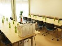共有スペースには大きな窓があり、観葉植物が置かれている。テーブルと椅子が置かれ、テーブルの上には数多くの飲み物が準備されている。