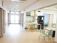 共有スペースには木調のテーブルと手すり付きの椅子が置かれている。廊下、壁、天井、テーブル、椅子の色は統一され、落ち着いた感じになっている。