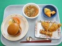 プレートの上に、揚げ物、野菜付きのハンバーグ、中華風スープ、フルーツといった和洋中の料理が載せられている。