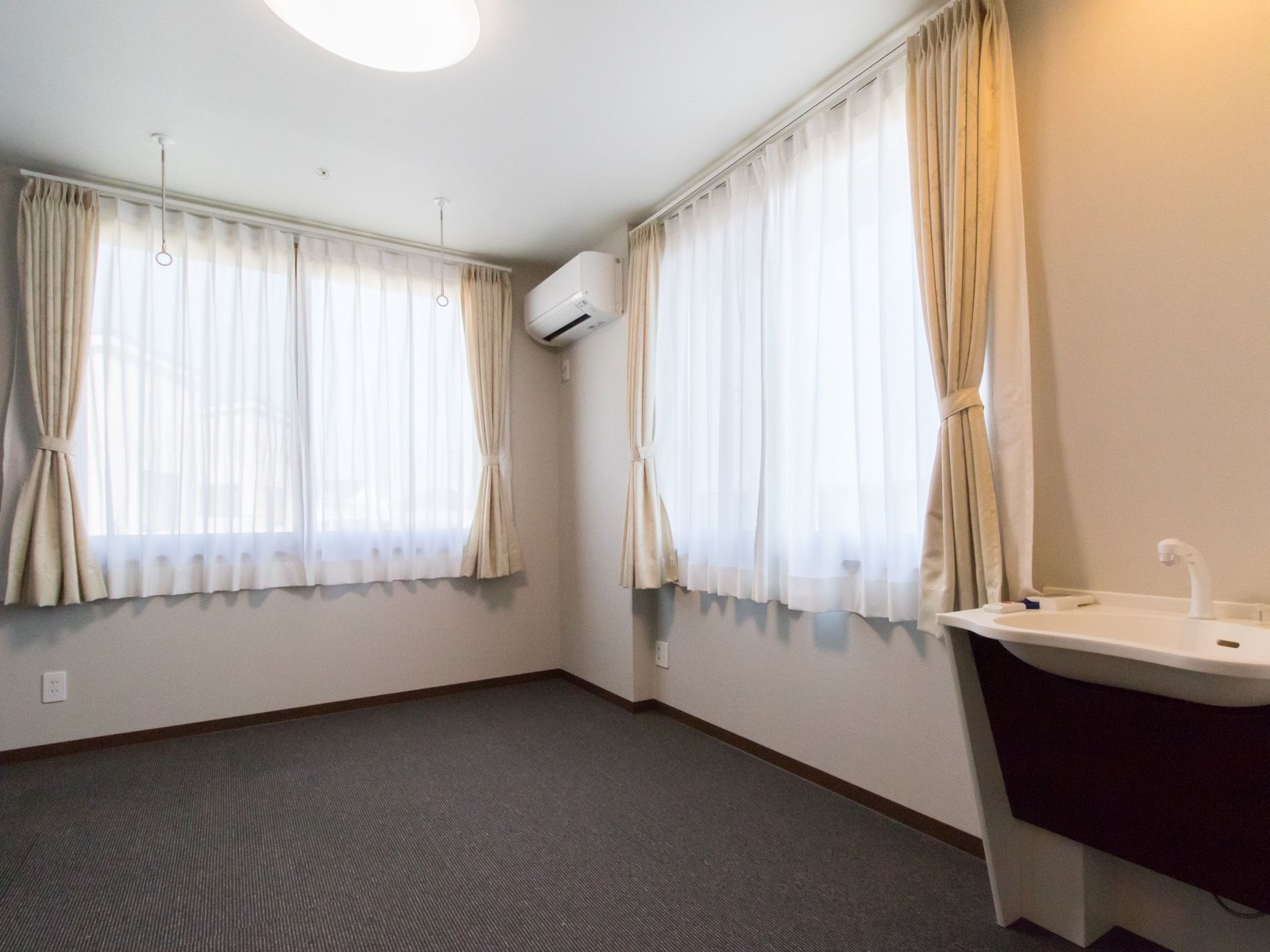 部屋の窓は２か所にあるので、日差しがよくはいり、明るい部屋となっている。エアコンが上部に設置され、洗面台もある。