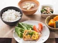テーブルに一食分の食事が置かれている。ご飯と汁物、メイン料理の他に小鉢に入れられた副菜が２品並べられている。