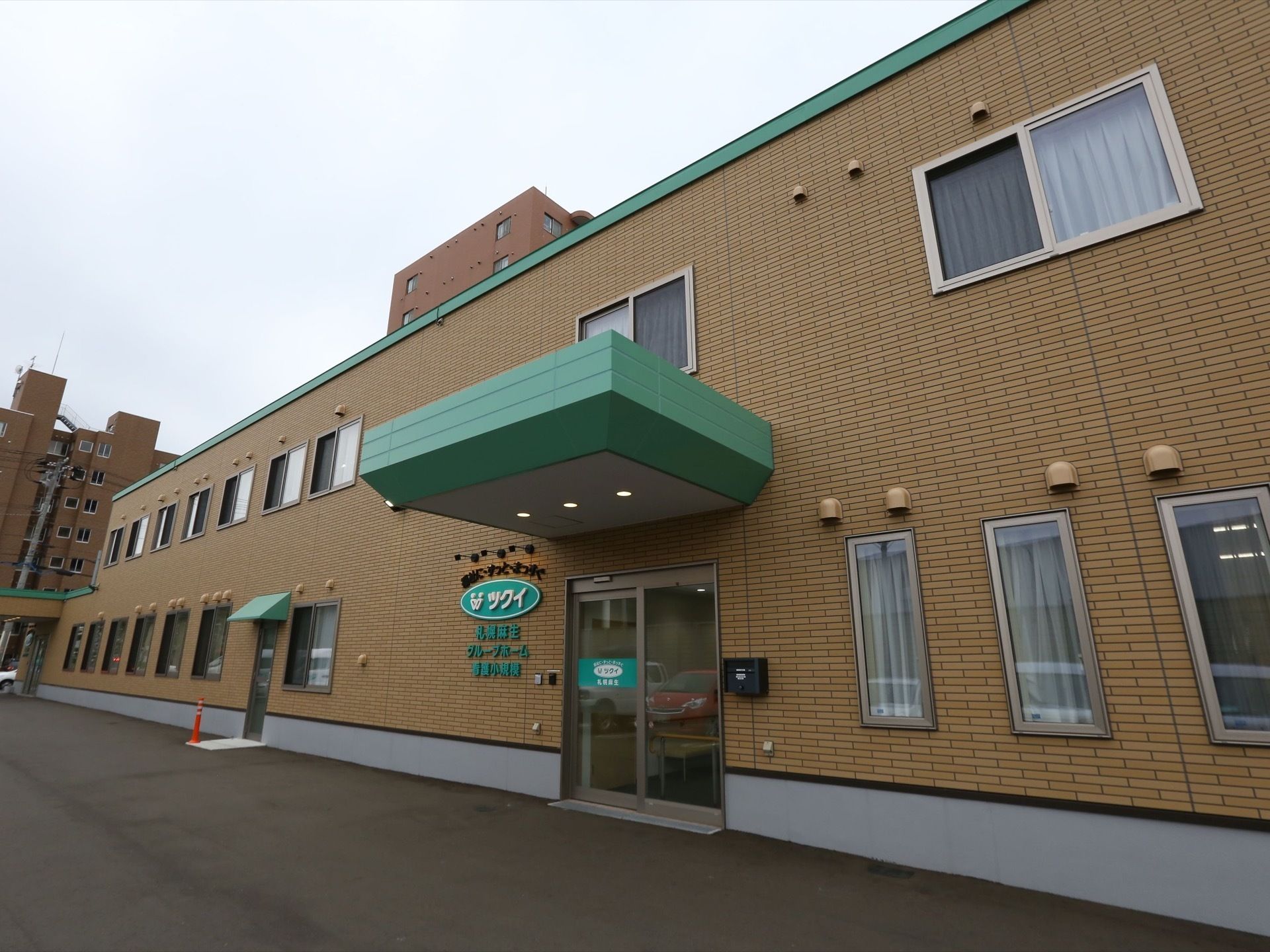 2階建てのグループホームである。玄関はガラス張りの自動ドアで外壁にはポストが設置され、大きく施設名が書かれている。
