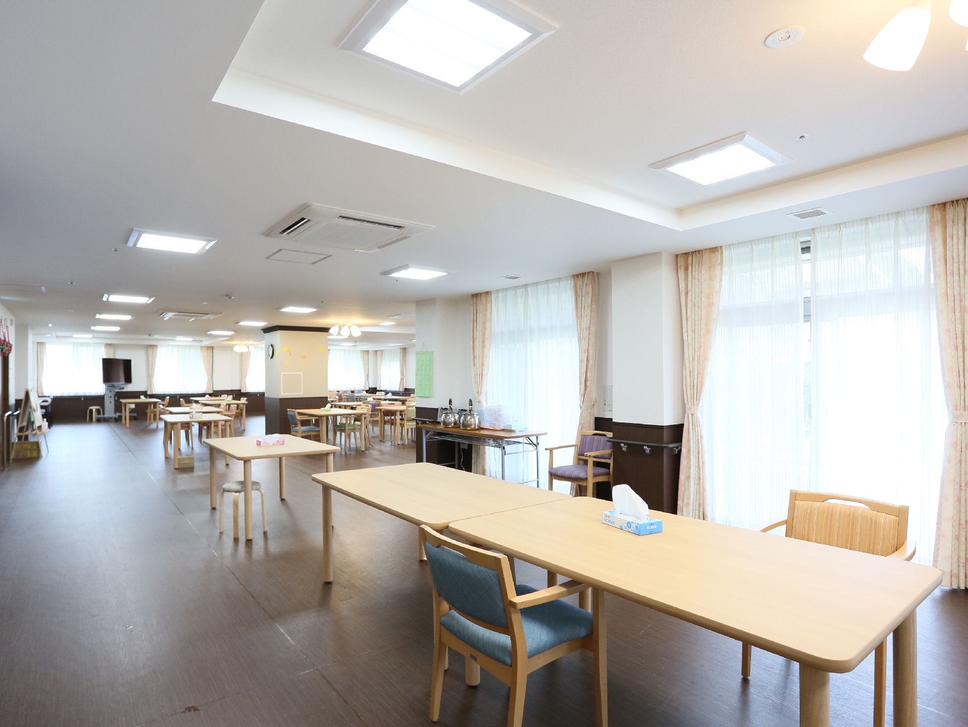 壁に手すりが付き、窓が多くて明るい、テーブルがたくさん並んだ広い食堂