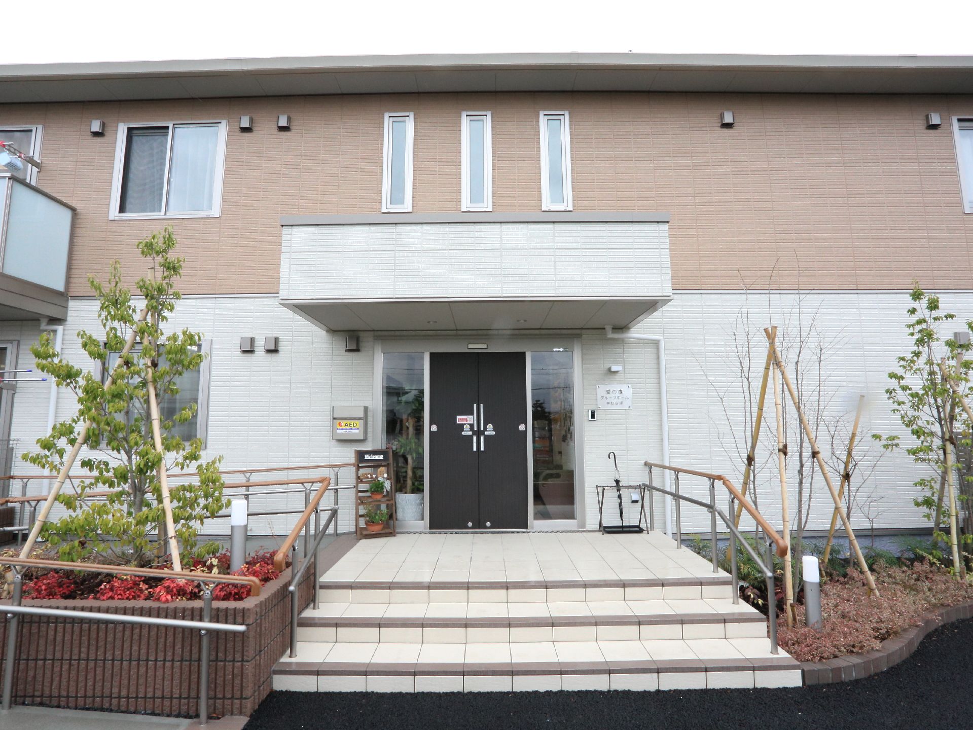 花壇があり、手すり付きの階段とスロープが設置されたエントランス