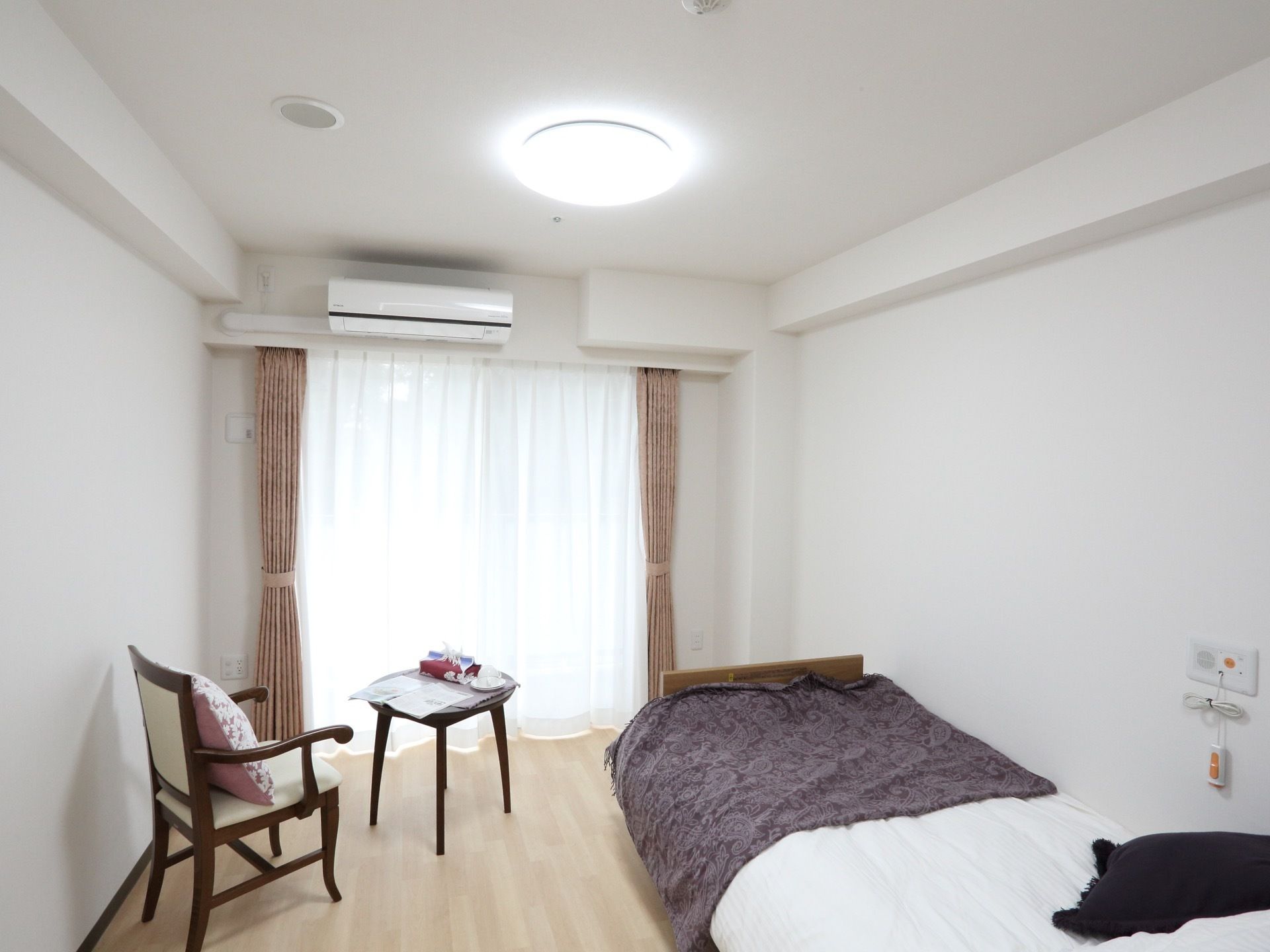 白を基調とした、明るい部屋である。ピンク色のカーテンがセットされた、掃き出し窓を完備。エアコンも備えつけられている。