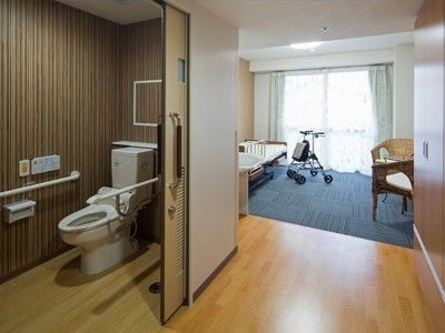 室内に大きな個室トイレがあり、介護ベッドが設置されたバリアフリーな居室